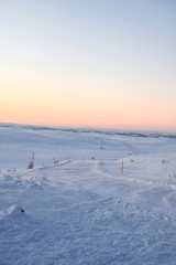 Fototapeta na wymiar pink dawn in the tundra everywhere white snow nobody road