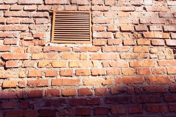 A small window with a lattice on an old brick wall