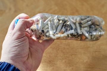 A plastic bottle containing cigarette butts in a man's hand