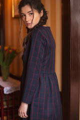 Portrait of young beautiful cute cheerful woman in dark blue dress looking and posing for camera in cafe background
