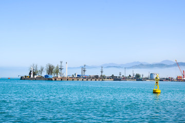 industrial port blue water clear weather white fog on the backgroundyellow lighthouse landscape