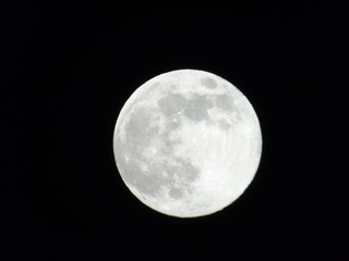 Genova, Italy - 03/20/2019: An amazing photography of the full moon over the city of Genova by night with a great clear sky in background and some stars