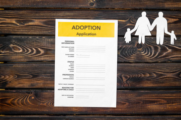 Adoption application near family figures on wooden background top view