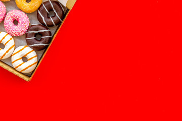 Donuts with different flavors in box on red background top view mockup