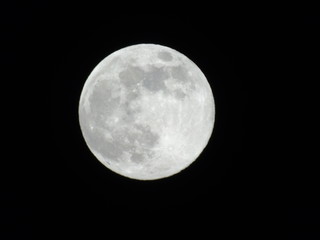Genova, Italy - 03/20/2019: An amazing photography of the full moon over the city of Genova by night with a great clear sky in background and some stars