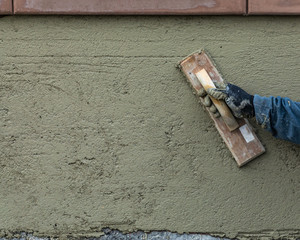Worker Smoothing Cement with Wooden Float At Construction Site