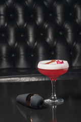 SIMULATOR OF ORAL SEX FOR WOMEN on a black background, next to it stands a glass of red alcoholic cocktail decorated with roses. Sex toys. Place for text. Sex shop concept. Copy space. Adult store.