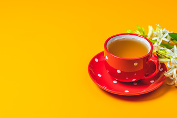 Red in white dotted cup of tea beside white hyacinths