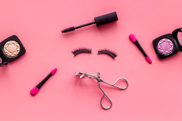 decorative cosmetic set with lash curler and mascara on pink woman desk background top view