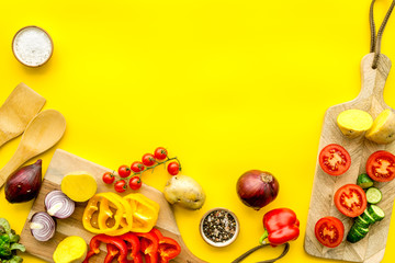 Vegan food cooking with raw vegetables on yellow background top view mock up