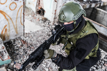 Fototapeta premium Young Special forces SWAT soldier aiming with assault rifle gun at the ruined building war terrorist battle zone