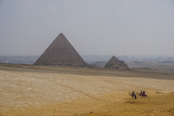 Giza, Egypt: Tourists ride camels on the sand near the Khufu Pyramid Complex.