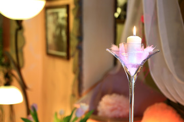 Płonąca świeca w kielichu z piórmi, dekoracja w restauracji.