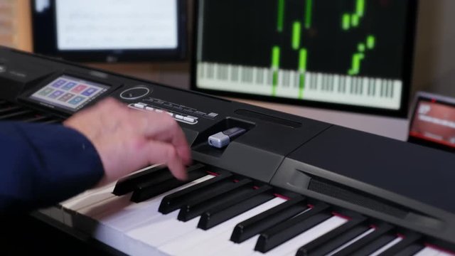 A musician records a song from a keyboard onto his computer in the background.  	