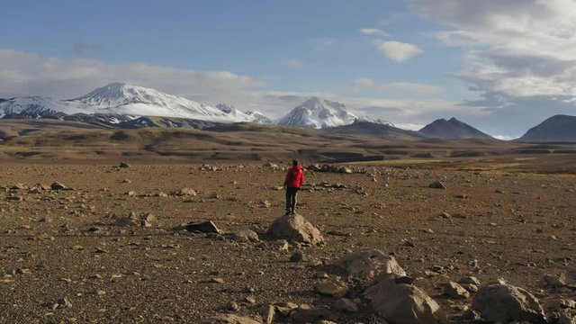 Aerial drone shot of a man ralking towards mountains in Iceland