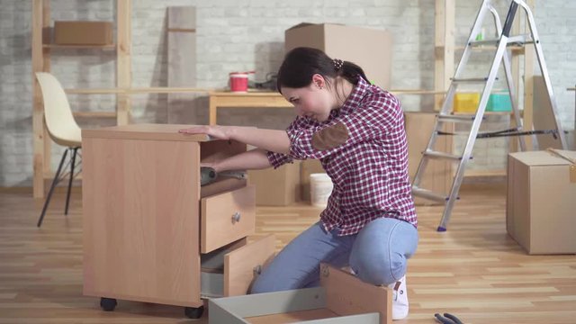 Young woman engaged in the assembly of the bedside table