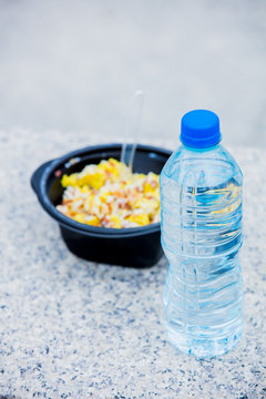 Water in blastic bottle and rise box for a lunch on stone