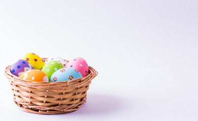 Happy Easter. Easter eggs concept. Closeup Colorful Easter eggs in nest and basket on white paper background.
