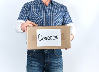 man in casual clothes holding a brown paper box with the inscription donation