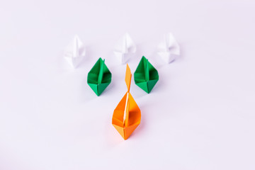 Leadership concept using orange paper ship among white and green. Motivation concept.