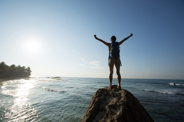 Successful woman outstretched arms on seaside rock cliff edge