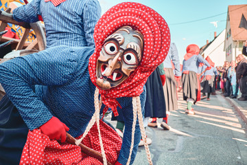 Pretty witch with red hood and blue robe, looks into the camera. Street Carnival in Southern Germany - Black Forest.