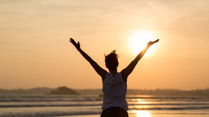 Fototapeta na wymiar Woman open arms on sunset beach Rear View