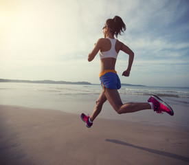 young fitness woman running at sunrise beach