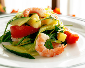 Spring creative fresh salad of shrimp, avocado, tomato, potato, cucumber. Sunlight from the window. Dish on a white plate. Close-up