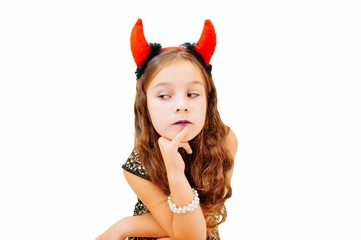 A little girl with devil horns in an evening dress sits and emotionally expressing emotions,...