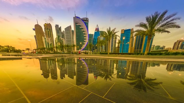 TIME LAPSE: Scenary of Doha West Bay skyline at sunset to night, reflecting in the water of park in Downtown. Modern glassed skyscrapers of Doha skyline in Qatar, Middle East, Arabian Peninsula.