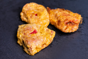 Delicious stuffed fried peppers on black slate .