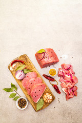 Assortment of slicing raw pork tenderloin with vegetables and spices. Cooking meat background, fresh brisket boneless steak on stone background, close up, top view, copy space.