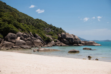 Fototapeta na wymiar Turquoise water, granite rocks and tropical trees in the white sand