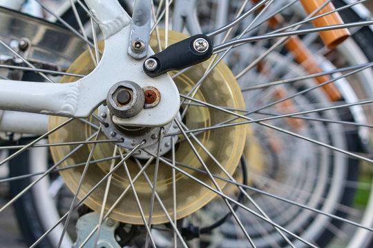 Close up. Details of rear bicycle wheel gears - spoke protector, cluster, derailleur and spokes with blurred rear wheels of parked rental bikes in background