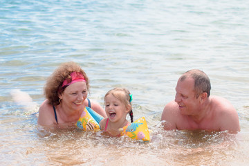 Grandparents And Granddaughter swimming in the sea, they smile and happyness