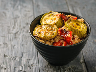 Black bowl with a salad of baked vegetables and the cooked quinoa. Vegetarian dish. Natural plant food. The view from the top.