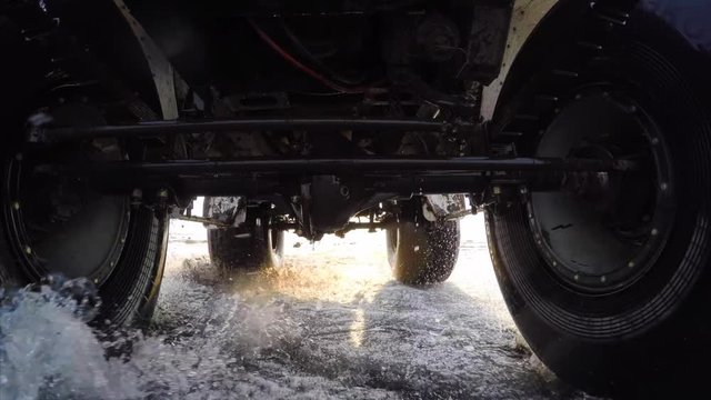Dynamic gopro view from car bottom side. Swamp buggy is driving fast on melting snow and puddles