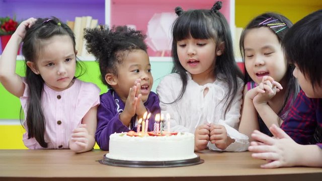 Group diversity kids blowing birth day cake.
