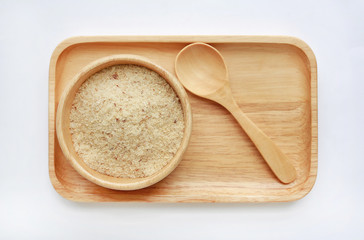 Dried shredded fish floss in wood bowl and spoon on wooden tray against white background.