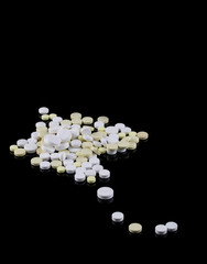 Fototapeta na wymiar Scattered round medicinal tablets on a black background