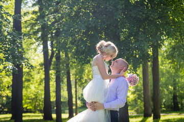Russian bride and groom together in green city park