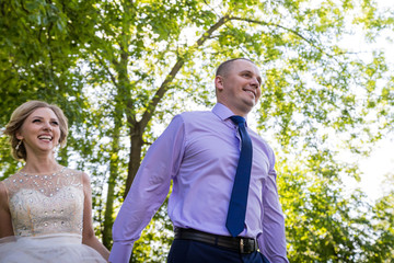 Russian bride and groom together in green city park