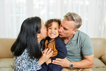Parents kissing daughter