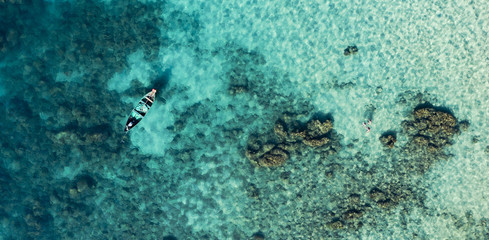 View from above, stunning aerial view of a long-tail boat and tourists who do snorkelling in a beautiful and turquoise sea, Phi Phi Island, Maya Bay, Thailand.
