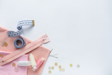Sewing accessories and fabric on a white background. Fabric, sewing threads, needles, buttons and sewing centimeter. top view, flatlay