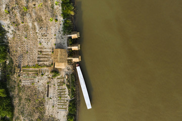 Stunning aerial view of a beautiful traditional hut with a wooden boat anchored on the Mekong...