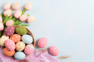 Happy easter! Colourful of Easter eggs in nest with Pink tulips and Feather on blue sky wooden...