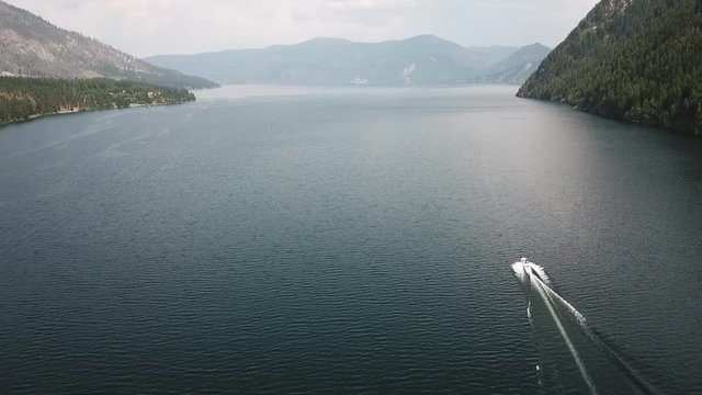 Aerial view of powerboat speeding across Lake Pend Oreille near Bayview, Idaho with mountains in the distance.