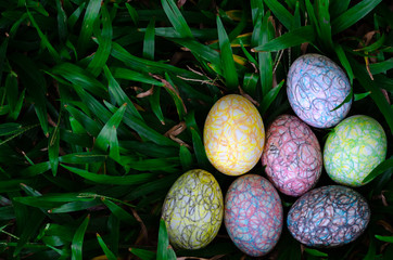 Group of colorful Easter egg painting by the crayon hiding in green grass at the park.